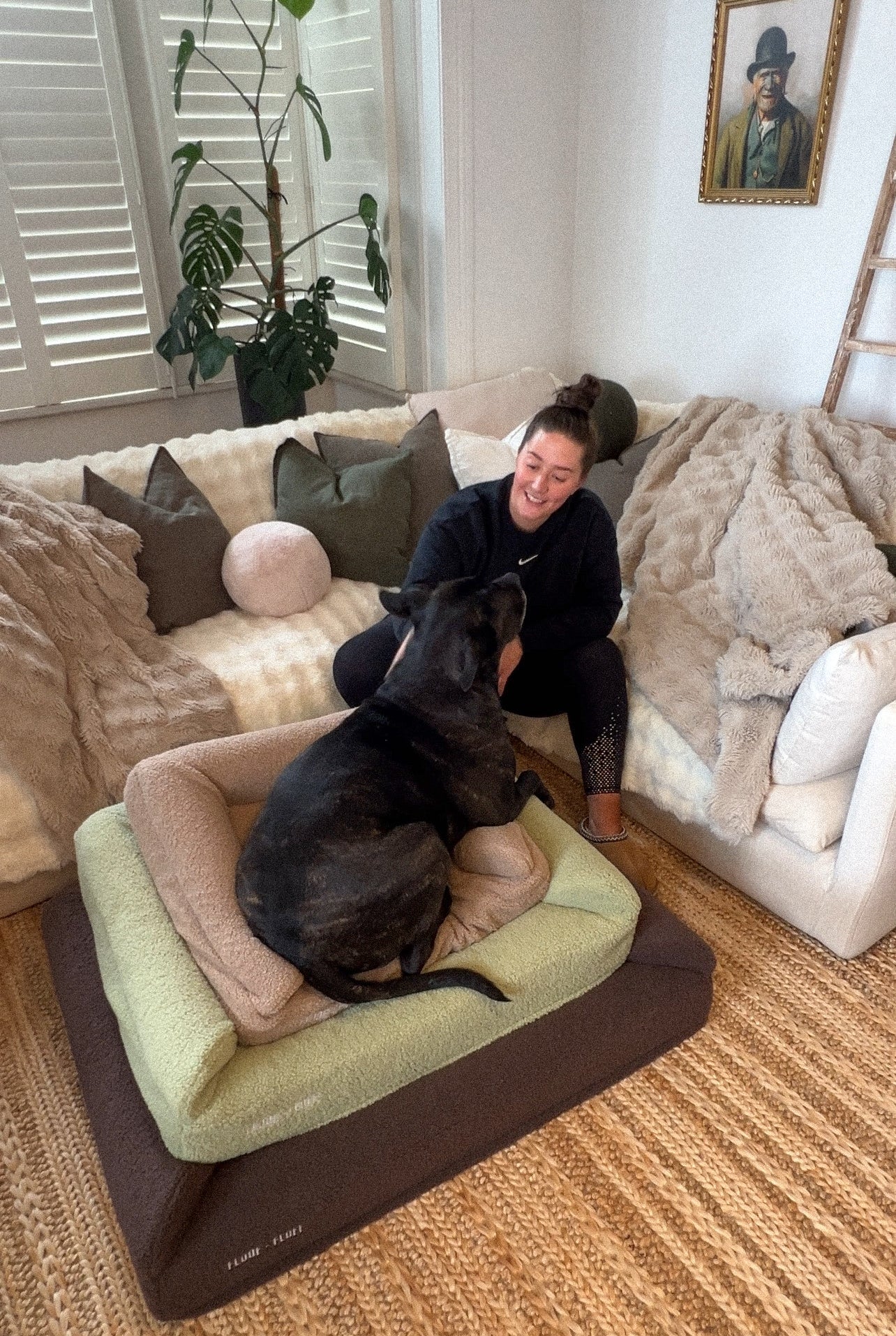 The founder of floof n fluff sitting on a couch with her dog on top of a pile of Floof n Fluff dog beds