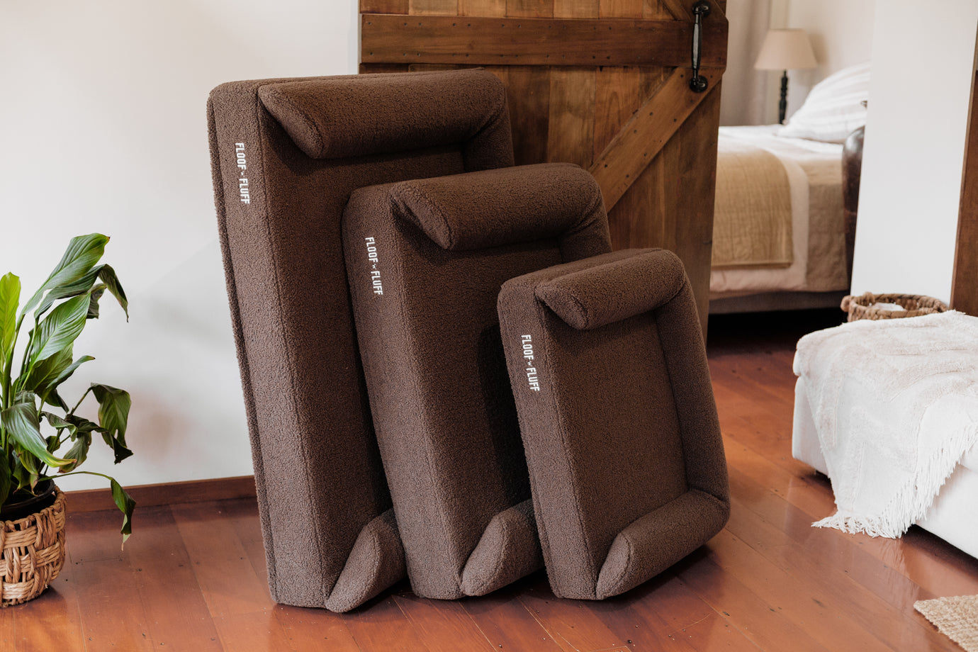Set of brown Floof n Fluff pet beds on a wooden floor with a bedroom in the background